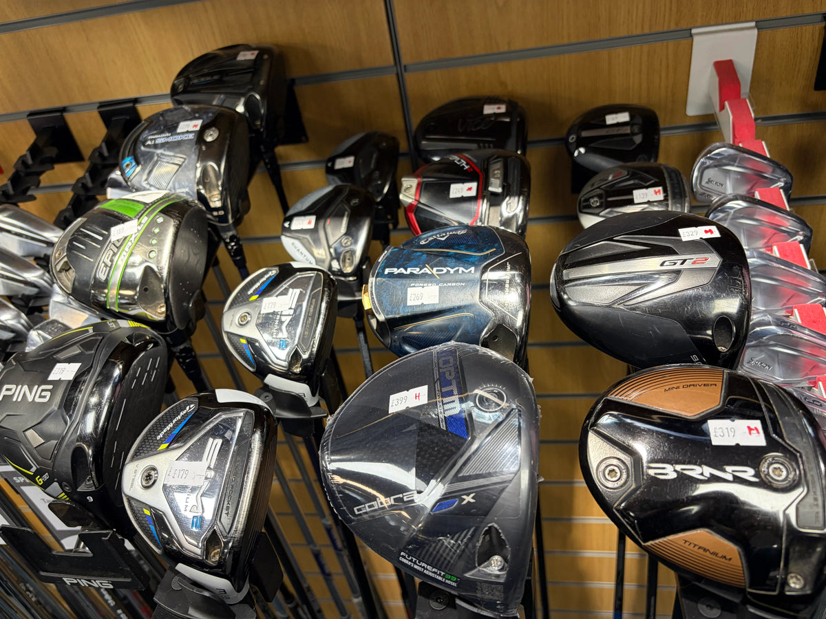 Golf clubs in a bag on a course at sunset